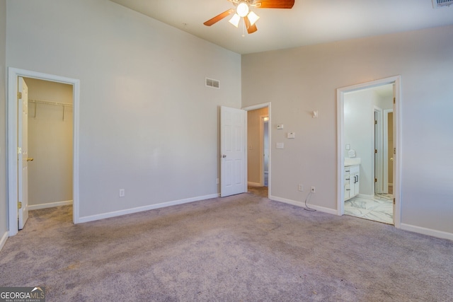 unfurnished bedroom featuring ceiling fan, light carpet, a spacious closet, and high vaulted ceiling