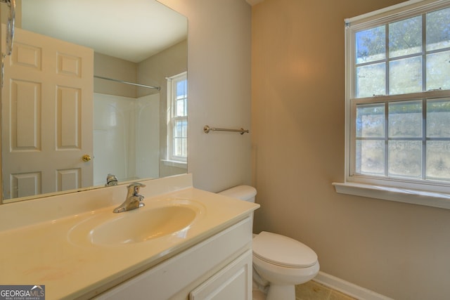 bathroom with a shower, a healthy amount of sunlight, vanity, and toilet