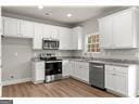 kitchen with light hardwood / wood-style floors, white cabinetry, and stainless steel appliances