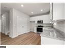 kitchen featuring light stone counters, white cabinets, hardwood / wood-style flooring, and stainless steel range oven