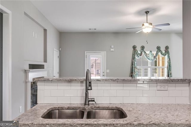 kitchen featuring ceiling fan, light stone countertops, sink, and a wealth of natural light