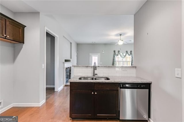 kitchen featuring sink, light hardwood / wood-style floors, dark brown cabinetry, stainless steel dishwasher, and light stone counters