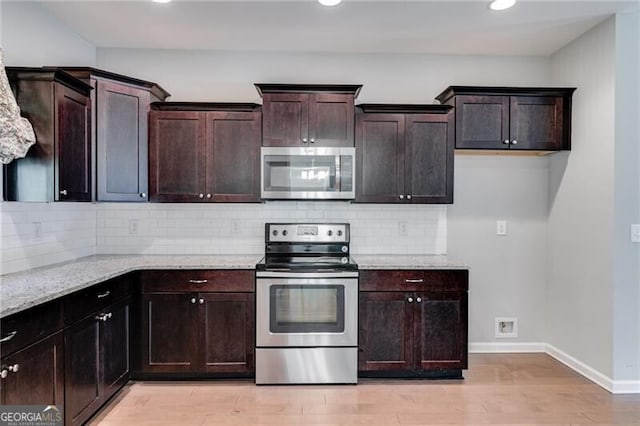 kitchen featuring dark brown cabinets, backsplash, stainless steel appliances, light stone counters, and light hardwood / wood-style floors