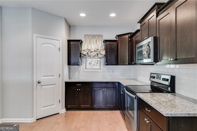 kitchen featuring dark brown cabinetry, light stone countertops, stainless steel appliances, and light wood-type flooring