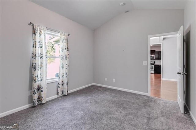 carpeted spare room featuring lofted ceiling