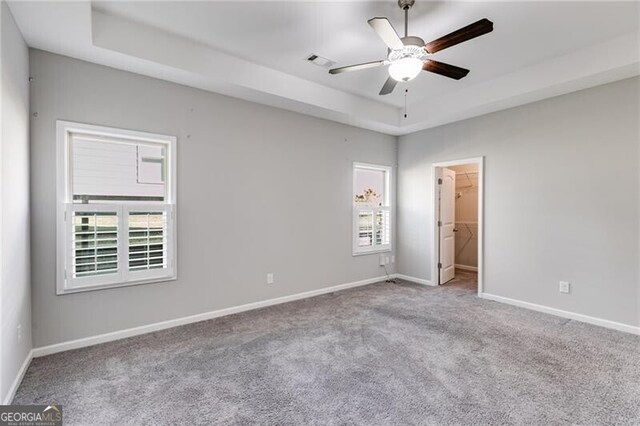 spare room with light carpet, a tray ceiling, and ceiling fan