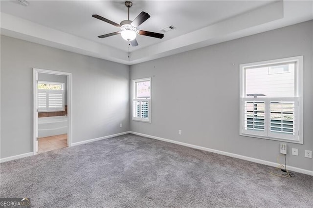 unfurnished bedroom with connected bathroom, multiple windows, and ceiling fan