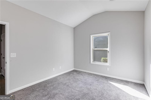 carpeted empty room with vaulted ceiling