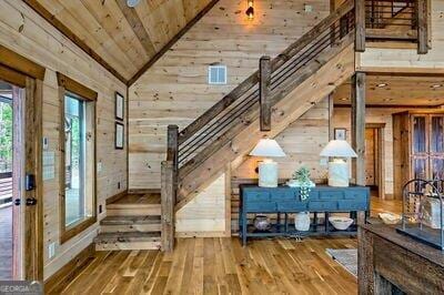 entrance foyer with wood walls, wood ceiling, high vaulted ceiling, and hardwood / wood-style flooring