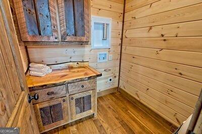 bathroom featuring hardwood / wood-style flooring and wooden walls