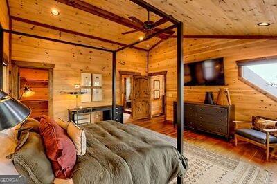 bedroom with wood walls, vaulted ceiling with skylight, wooden ceiling, and hardwood / wood-style flooring