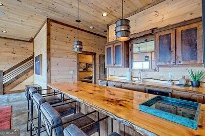 kitchen with hanging light fixtures, butcher block countertops, wooden walls, and a kitchen breakfast bar