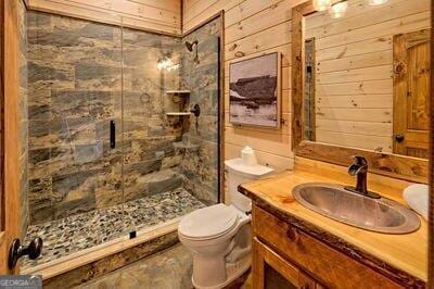 bathroom with wooden walls, toilet, a shower with door, and vanity