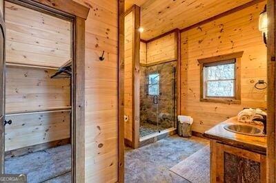 bathroom featuring wood walls, vanity, a shower with shower door, and wooden ceiling