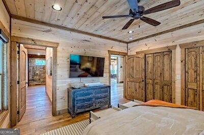 bedroom featuring wooden walls, ceiling fan, hardwood / wood-style floors, and wooden ceiling