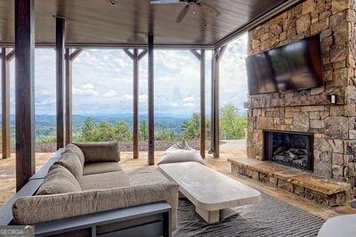 sunroom / solarium with an outdoor stone fireplace and ceiling fan