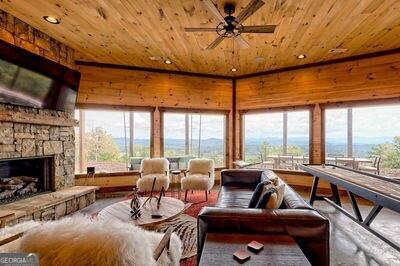 living room featuring a stone fireplace, hardwood / wood-style flooring, and wooden ceiling