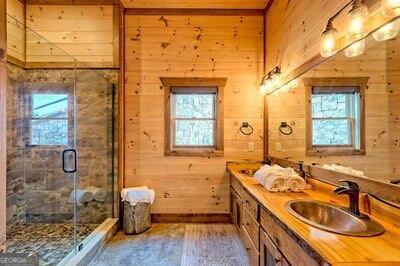 bathroom with vanity, wood walls, and a healthy amount of sunlight