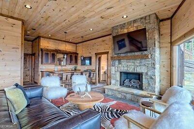 living room with a fireplace, wood ceiling, and wooden walls