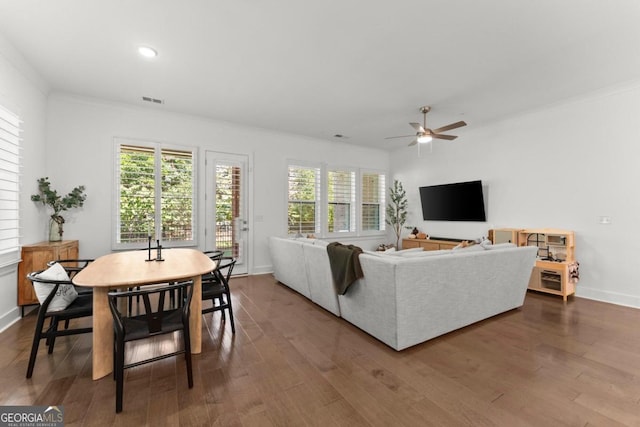 living room featuring dark wood-type flooring, ornamental molding, and ceiling fan