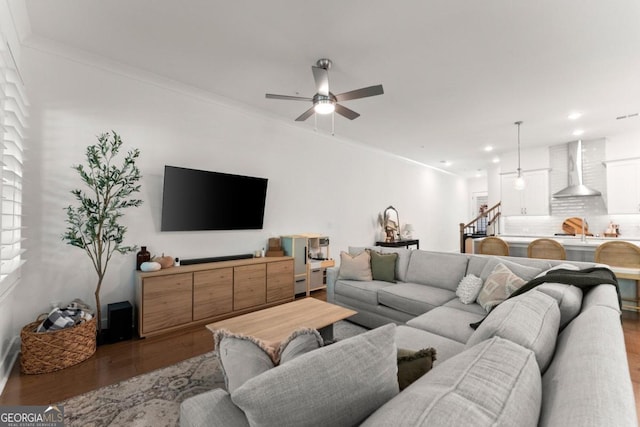 living room with wood-type flooring, ornamental molding, and ceiling fan