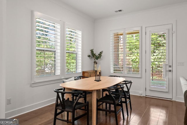 dining area with ornamental molding, dark hardwood / wood-style flooring, and a wealth of natural light