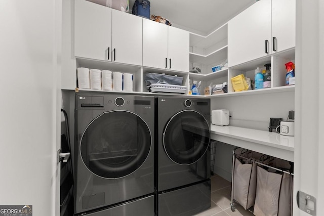 clothes washing area with cabinets, light tile patterned floors, and washing machine and dryer