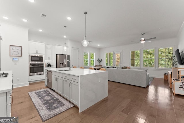 kitchen featuring appliances with stainless steel finishes, hardwood / wood-style flooring, sink, and white cabinets