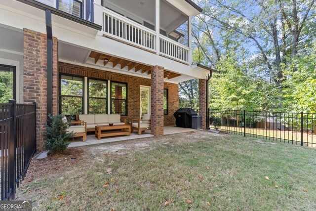 back of house with outdoor lounge area, a patio, a balcony, and a lawn