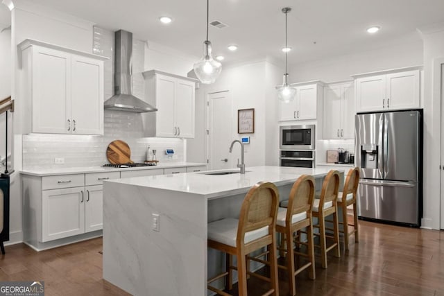 kitchen featuring white cabinets, hanging light fixtures, sink, wall chimney range hood, and stainless steel appliances