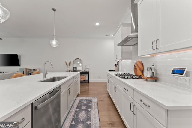 kitchen with hardwood / wood-style floors, stainless steel appliances, sink, pendant lighting, and white cabinetry