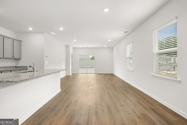 kitchen with light stone counters, sink, dark hardwood / wood-style flooring, and gray cabinetry