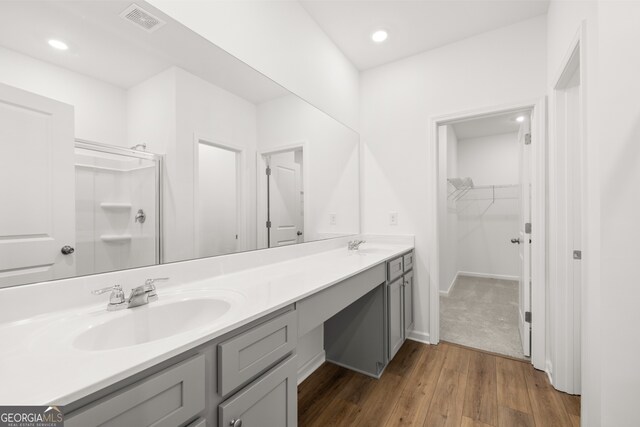 bathroom with wood-type flooring, walk in shower, and vanity