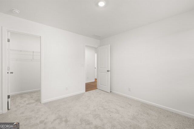 unfurnished bedroom with light colored carpet, a closet, and a walk in closet