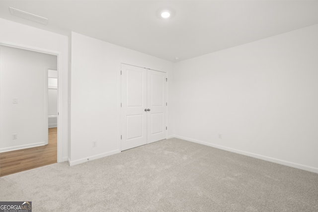 unfurnished bedroom with light carpet and a closet