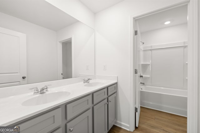 bathroom with washtub / shower combination, hardwood / wood-style floors, and vanity