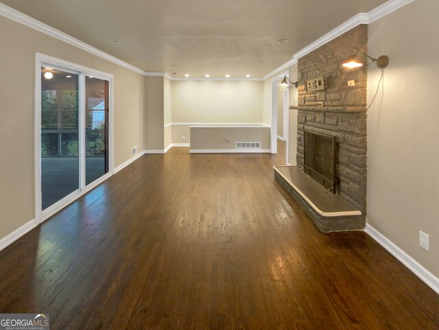 unfurnished living room with crown molding, a stone fireplace, and dark hardwood / wood-style floors