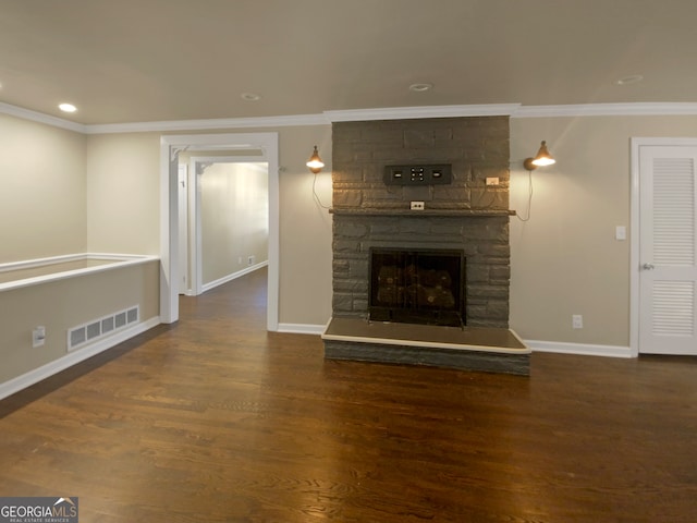 unfurnished living room featuring dark hardwood / wood-style floors, ornamental molding, and a stone fireplace