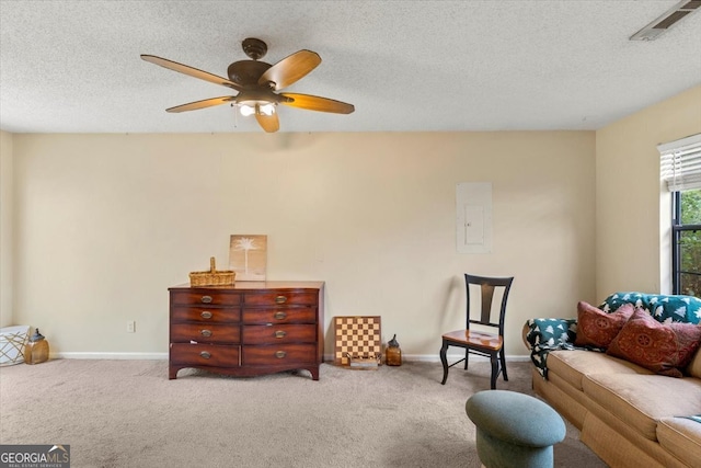 sitting room featuring ceiling fan, light colored carpet, a textured ceiling, and electric panel