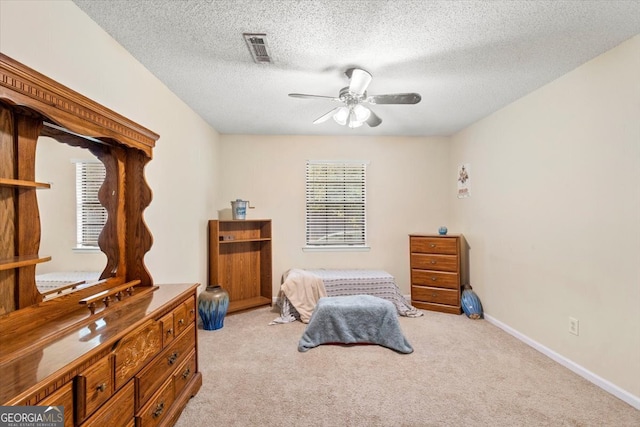 carpeted bedroom with ceiling fan and a textured ceiling