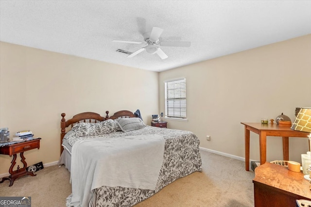 bedroom with a textured ceiling, ceiling fan, and light colored carpet