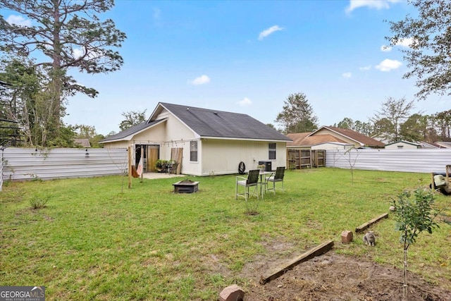 back of property featuring a fire pit and a yard