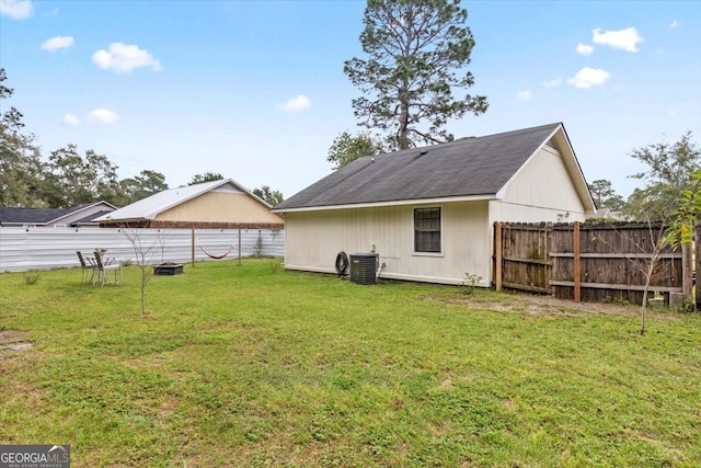 rear view of house with central AC and a lawn