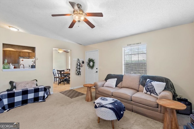 living room with light colored carpet, a textured ceiling, and ceiling fan