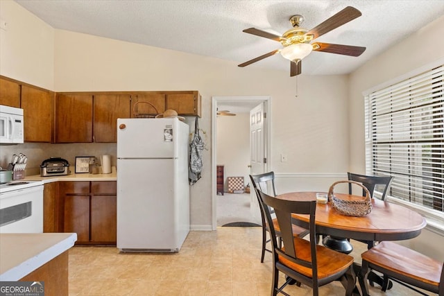 kitchen featuring ceiling fan, a textured ceiling, vaulted ceiling, and white appliances