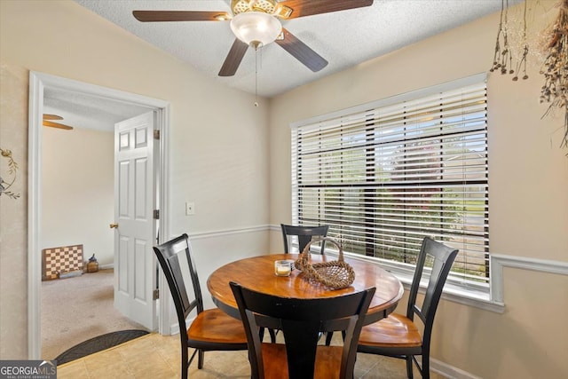 dining room featuring light carpet, ceiling fan, and a textured ceiling