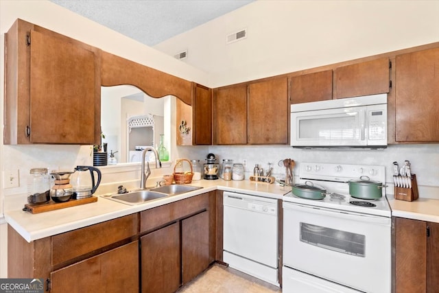 kitchen featuring a textured ceiling, sink, white appliances, and decorative backsplash