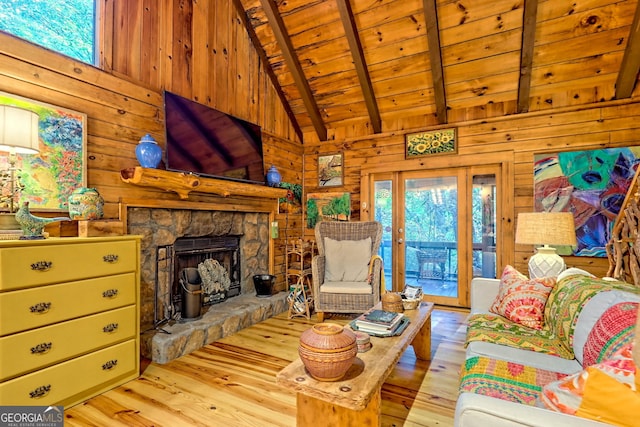 living room with wood walls, light hardwood / wood-style floors, lofted ceiling with beams, wooden ceiling, and a fireplace