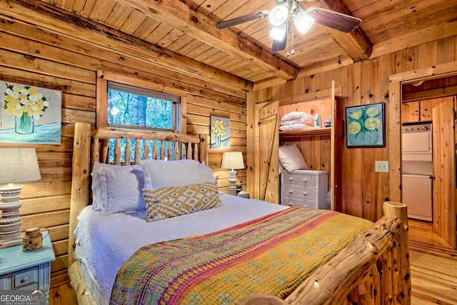 bedroom with beamed ceiling, light wood-type flooring, stacked washer / dryer, and wooden ceiling