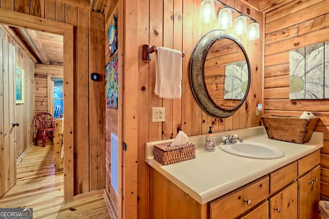 bathroom featuring wood-type flooring, vanity, and wood walls